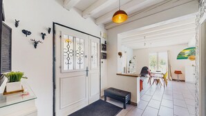 A hallway with a bench, a glass display case with plants, and a door with decorative glass panels. - Belle Maison vue montagnes (Bidarray)
