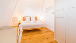 Een slaapkamer met een bed, nachtlampjes, een kledingkast en een hanglamp.