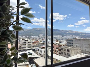 A view from a window overlooking a cityscape with buildings and mountains in the distance. - Apartment with a Movie Theater, Ecuadorian Style, and Self-Check-In (Quito)