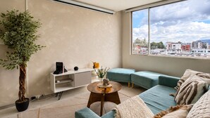 Un salon moderne avec un canapé, une table basse et une grande fenêtre donnant sur la ville.
