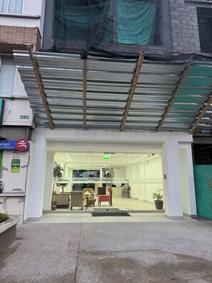 A bank's entrance with a covered entrance, a reception area with chairs, and a potted plant.