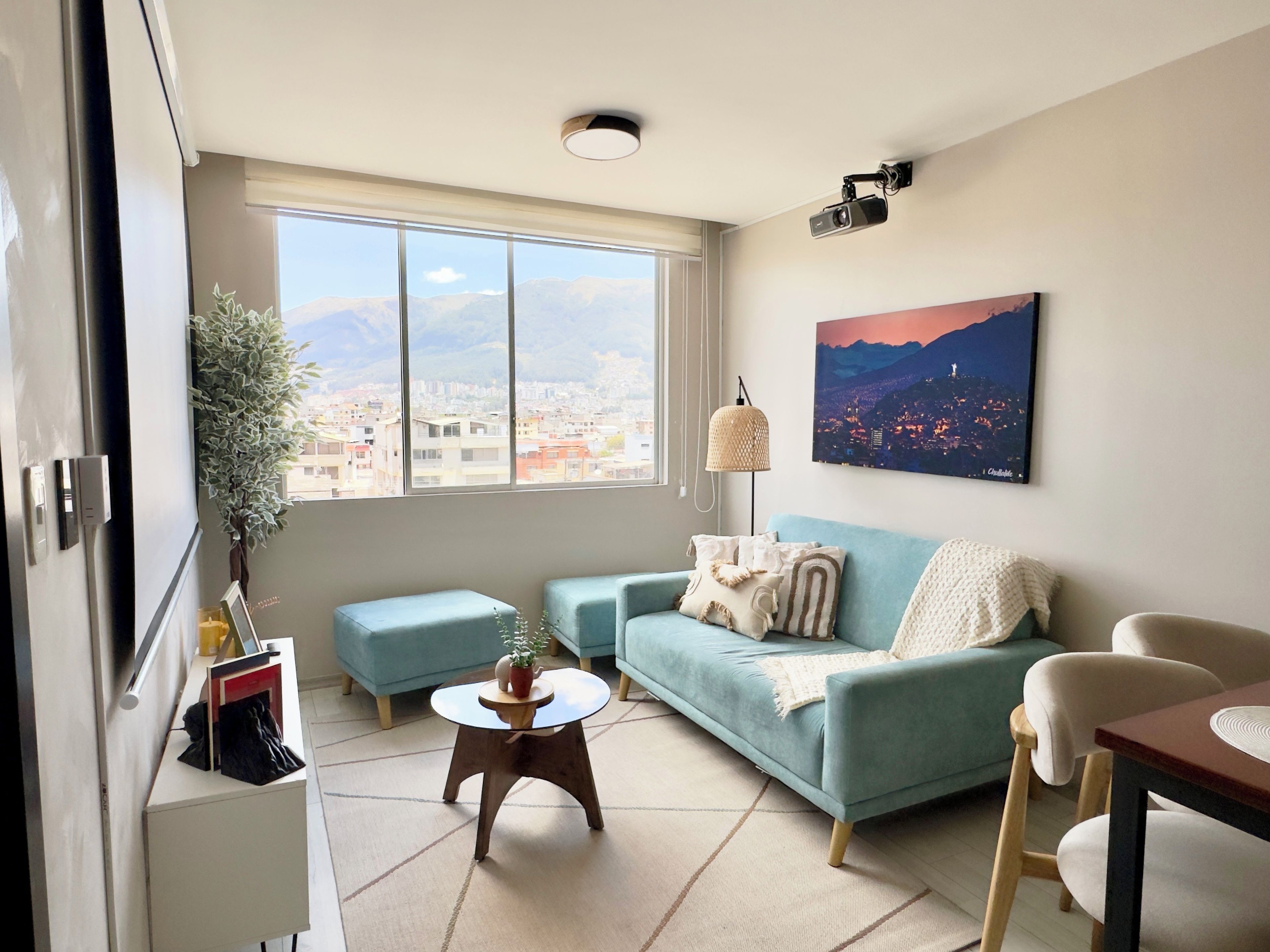 A modern living room with a large window, a sofa, a coffee table, and a painting on the wall.