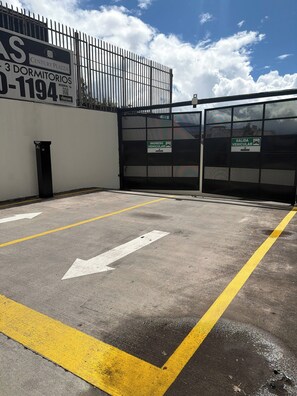 A parking area with directional arrows, a gated entrance, and a sign indicating a vehicle exit. - Apartment : private cinema : View : WiFi : Alexa : Capacity 4 persons (Quito)