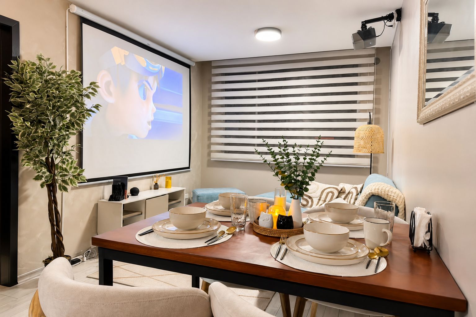 A dining area with a table set for four, a projector screen, a plant, and a window with blinds.