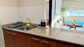 A kitchen with a granite countertop, stainless steel sink, and wooden cabinets.