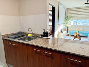 Une cuisine dotée d’un plan de travail en granit, d’un évier en acier inoxydable et de meubles en bois.