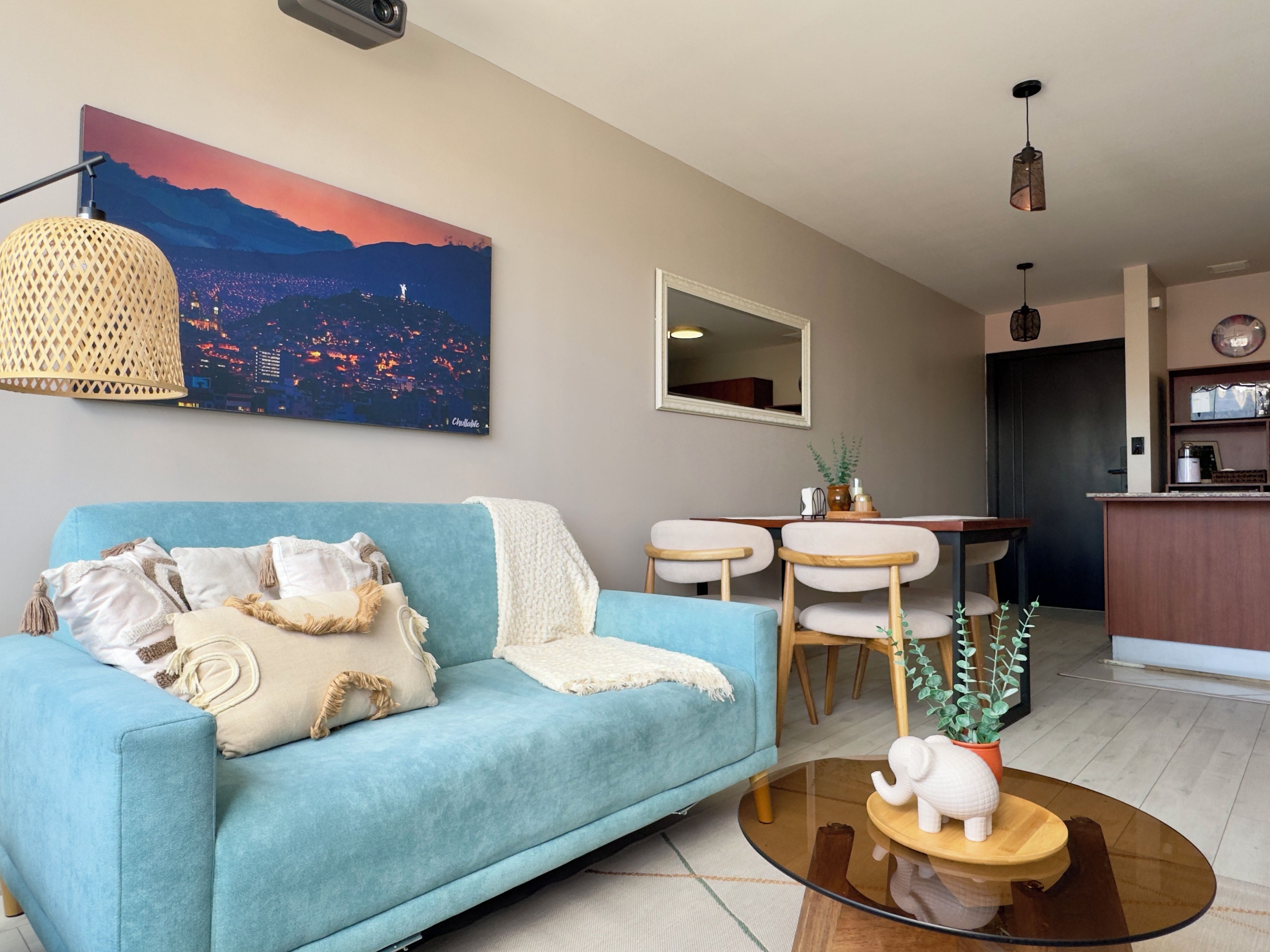 Ein Wohnzimmer mit einer Couch, einem Couchtisch, einem Gemälde und einem Essbereich mit Stühlen und einem Tisch.