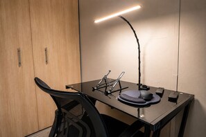 A modern office desk with a lamp, a chair, and a small table with a hat and a mouse. - Apartment : private cinema : View : WiFi : Alexa : Capacity 4 persons (Quito)