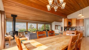 Un vaste espace de vie comprenant une grande table et des chaises en bois, une cheminée et une cuisine avec des meubles en bois.