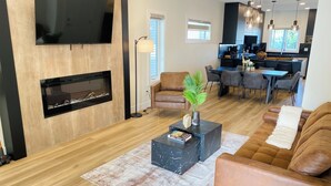 Un salon moderne avec une cheminée, un téléviseur à écran plat, une table basse et un canapé.