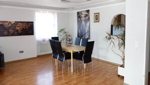 A dining area with a wooden table and chairs, a world map on the wall, and a large elephant painting. - Spacious lodging near the industrial park (5 beds) (Bielefeld)