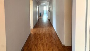 Un long couloir étroit, doté d’un plancher en bois et de murs blancs.