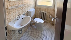 A bathroom with a toilet, sink, and window. - Spacious lodging near the industrial park (5 beds) (Bielefeld)
