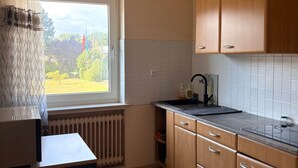 Une cuisine avec une fenêtre, un radiateur et des placards en bois.