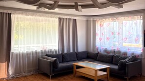A modern living room with a sectional sofa, a wooden coffee table, and a decorative ceiling. - Spacious lodging near the industrial park (5 beds) (Bielefeld)