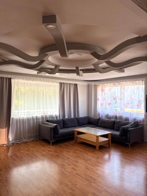 A modern living room with a sectional sofa, a wooden coffee table, and a decorative ceiling.