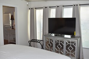 Een hotelkamer met een bed, een televisie op een kast en een raam met gordijnen.