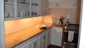 A kitchen with white cabinets, a granite countertop, a stainless steel oven, and a tiled backsplash. - La Ferme - french for country farmhouse 3BR/1BA in Rogers. (Rogers)