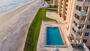 A beachfront hotel with a swimming pool, a beach, and a view of the ocean.