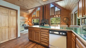 A wooden interior with a kitchen island, built-in appliances, and large windows.