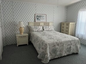 A bedroom with a polka dot wallpaper, a bed with floral bedding, a nightstand with a lamp, and a wardrobe. - Vibrant Active Adult 55+ community w/clubhouse, pool w/hot tub, fitness room. (Parrish)