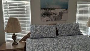 Une chambre à coucher avec un lit, deux oreillers, une table de chevet, une lampe et un tableau au mur.