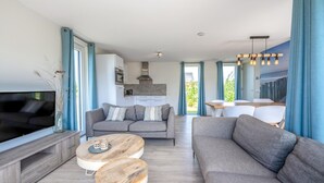 Un salon moderne avec un canapé gris, un téléviseur et une table basse en bois.