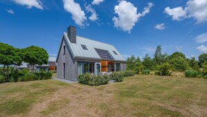 A modern house with a sloped roof, large windows, and a well-maintained lawn. - 3 bedroom cozy home in Kamperland (Kamperland)