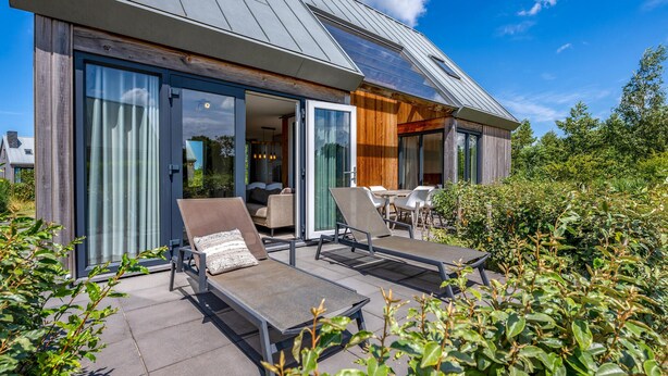 A modern house with a patio area featuring two lounge chairs and a table. - 3 bedroom cozy home in Kamperland (Kamperland)