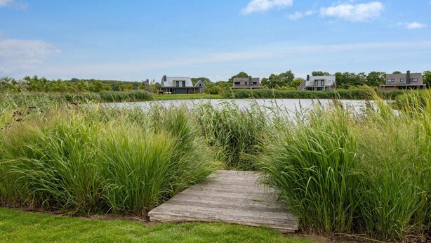 A wooden pathway leading to modern houses by a lake, surrounded by tall grass. - Gorgeous home in Kamperland with WiFi (Kamperland)