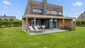 A modern two-story house with a covered patio area and a lawn. - Gorgeous home in Kamperland with WiFi (Kamperland)