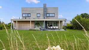 A modern two-story house with a flat roof, large windows, and a covered patio area with outdoor seating. - 3 bedroom awesome home in Kamperland (Kamperland)