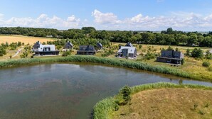 Ejendom ved søen med moderne huse, et bassin og grøn beplantning omkring.