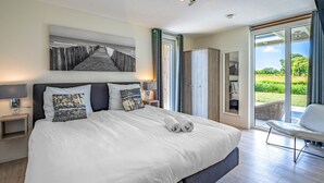 Et moderne hotelværelse med en stor seng, udsigt over landskabet og et siddeområde.