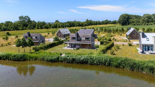 A modern residential area with houses featuring contemporary architecture, a small pond, and surrounding greenery. - Amazing home in Kamperland with WiFi (Kamperland)