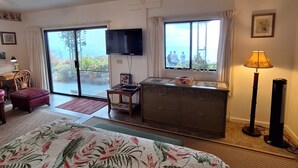 A hotel room with a bed, a TV, a desk, a dresser, and a large window.