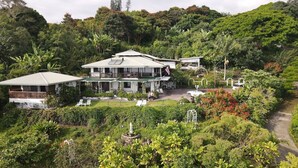 A large, two-story house surrounded by lush greenery and a garden.