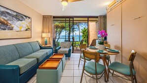 Ein modernes Wohnzimmer mit einer Couch, Sesseln, einem Esstisch und einem Deckenventilator.