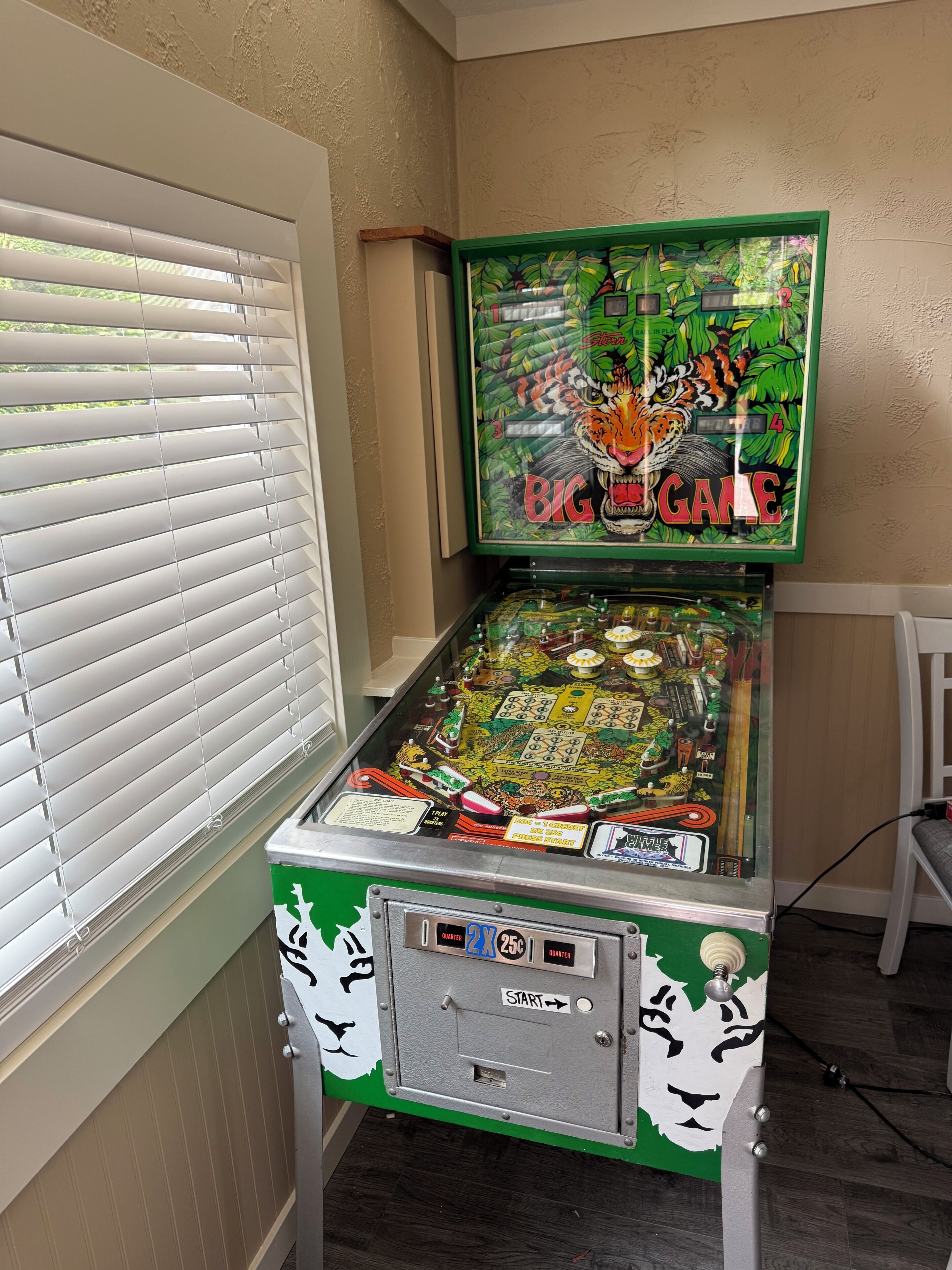 Una máquina de pinball con diseño de tigre, una ranura para monedas y un botón de inicio.
