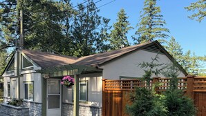 A two-story house with a stone foundation, a wooden deck, and a fenced backyard. - Welcome to Cultus Lake’s “Aspen” at The Cedars (Cultus Lake)