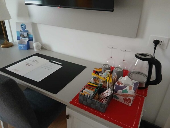 Una encimera de cocina con un tapete negro, un papel, una caja de pañuelos, una cesta de aperitivos, una cafetera y una copa de vino.