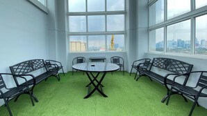 A conference room with a round table and six chairs, large windows with a city view, and green carpet. - Cozy Stay 1Br Apartment At 1 Cik Ditiro Residence (Jakarta)