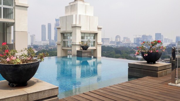 A rooftop infinity pool with a city skyline in the background. - Cozy Stay 1Br Apartment At 1 Cik Ditiro Residence (Jakarta)