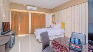 A hotel room with a bed, a desk, a chair, a table, and a minibar. - Nice And Minimalist Studio At Park View Condominium Apartment (Depok)