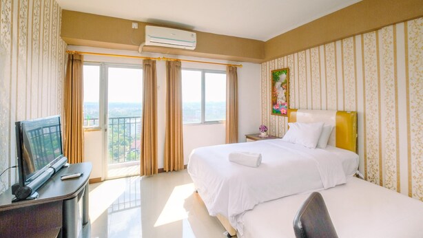 A hotel room with a bed, a desk with a TV, and a window with curtains. - Nice And Minimalist Studio At Park View Condominium Apartment (Depok)
