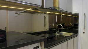 Una cocina moderna con encimera negra, pileta de acero inoxidable y horno integrado.