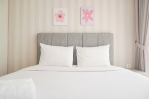 A neatly made bed with white linens and pillows, a striped wall with two flower paintings, and a window with curtains. - Best Price And Elegant 2Br At Menteng Park Apartment (Jakarta)