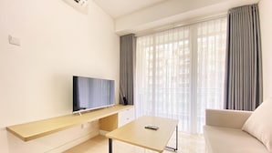 Un soggiorno moderno con una TV a schermo piatto su un supporto in legno, un tavolino e un divano.