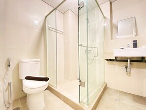 Ein modernes Badezimmer mit einer Duschkabine, einer Toilette und einem Waschbecken mit Spiegel.