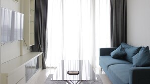 A modern living room with a sofa, a coffee table, and a TV mounted on the wall. - Elegant 1Br Apartment Landmark Residence Bandung Near 23 Paskal Shopping Center (Bandung)
